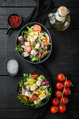 Greek salad with tomato, pepper, olives and feta cheese, on black wooden table background, top view flat lay