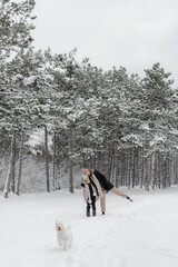 family walking in snow with dog