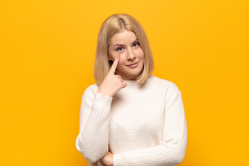 blonde woman keeping an eye on you, not trusting, watching and staying alert and vigilant