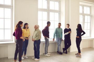 Office workers stand in a bright hall and communicate with each other during a break from work....