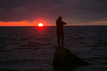 Man on the background of the sunset at sea.