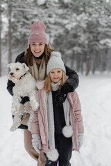 mother and child playing in snow with dog