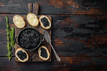 Canapes with black sturgeon caviar, on old dark  wooden table background, top view flat lay  with copy space for text