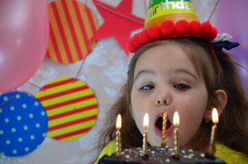 happy little girl celebrates birthday, balloons and decorations. the candles on the cake blow out. Happy group of children having fun at birthday party