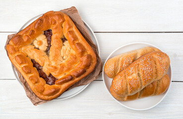 Apple pie and fresh buns on a light background. Top view, with in space to copy. Concept of culinary backgrounds.