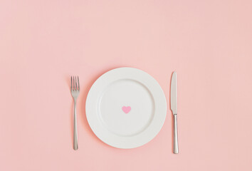 Festive romantic minimal table setting with a heart in a plate on a pink background. Love concept for Valentines or mothers day. Flat lay, top view, copy space.