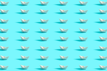 Pattern on  blue background and white paper boats. Symbol of summer and travel.
