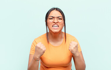 latin woman shouting aggressively with annoyed, frustrated, angry look and tight fists, feeling...