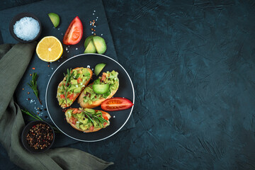 Vegetarian sandwiches with avocado, tomatoes and lemon on a black background. Top view, with space to copy. The concept of healthy eating.