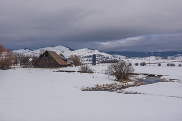 Water stream in snow and wooden barn in Hells Canyon area, Oregon