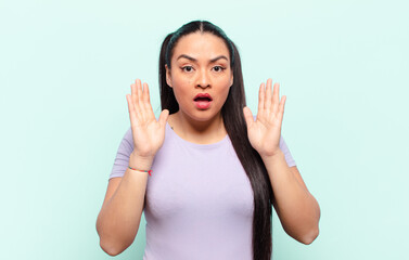 latin woman looking shocked and astonished, with jaw dropped in surprise when realizing something...