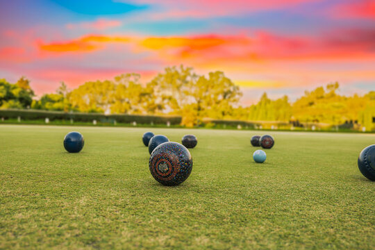 Lawn bowls balls in a field after the game with a colourful sunset