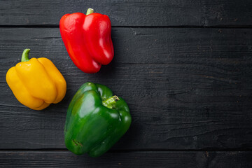 Sweet bell peppers, on black wooden table background, top view flat lay with copy space for text