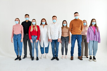 group of people in medical face masks during Covid second wave outbreak confidently posing at camera. new normal lifestyle concept with young people isolated in studio, portrait