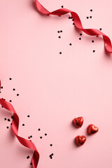 Happy Valentines day card with red ribbon, confetti, heart shaped sweets on pink background. Vertical banner, brochure, poster design.