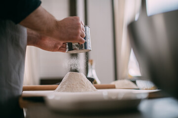 A male chef prepares dough at home in the kitchen