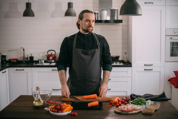 A male cook prepares vegetables at home in the kitchen