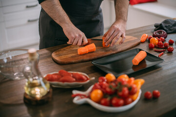 A male cook prepares vegetables at home in the kitchen