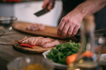 A male chef prepares fresh meat at home in the kitchen..