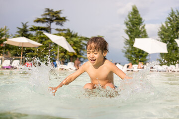 Cute little boy kid child splashing in swimming pool having fun leisure activity