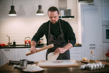 A male chef prepares noodles at home in the kitchen.