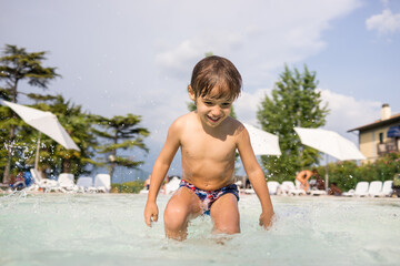 Cute little boy kid child splashing in swimming pool having fun leisure activity