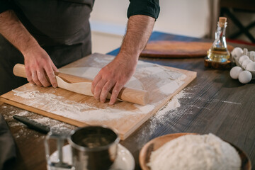 A male chef prepares noodles at home in the kitchen.