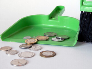 coins scattered on the floor are swept by a broom in a scoop