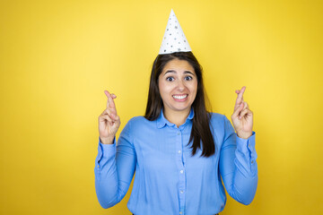 Young caucasian woman wearing a birthday hat over isolated yellow background gesturing finger...