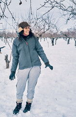 Vertical photo of the Happy caucasian girl smiling and warm and wearing a hat enjoying the snow.