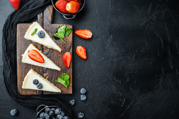 Cheesecake with blueberries and strawberries, on black background, top view flat lay with copy space for text