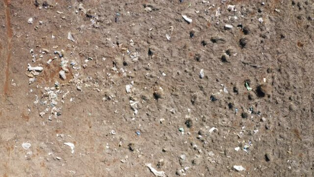 Top down view on garbage from landfill polluting countryside field. Wind blowed away consumer garbage, used shopping plastic bags and household waste. Ecology, nature environment problem. Aerial 4K
