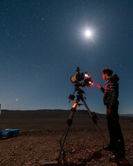 One astronomer man looking the night sky through an amateur telescope and taking photos to the...