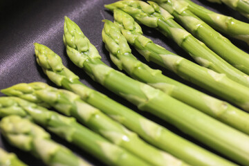 A bunch of ripe fresh asparagus on a black background, healthy organic food cooked at home.