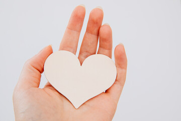 Obraz premium heart in hand. Woman holds a white wooden heart in her hands. Valentine's day. Give away a heart. Tender heart.