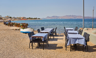 Fototapeta na wymiar Greek beach with traditional blue tables and chairs
