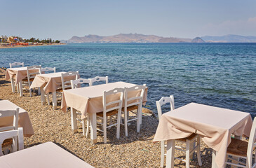 Fototapeta na wymiar Greek beach with traditional blue tables and chairs