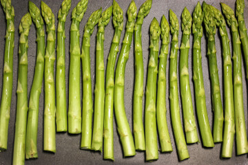 A bunch of ripe fresh asparagus on a black background, healthy organic food cooked at home.