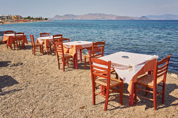 Greek beach with traditional blue tables and chairs