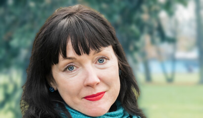 Obraz premium close-up portrait of woman, middle-aged 45-year-old brunette stands against the background of the park
