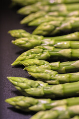 A bunch of ripe fresh asparagus on a black background, healthy organic food cooked at home.