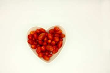 Red heart formed by red cherry tomatoes contained in a heart-shaped bowl gourmet food