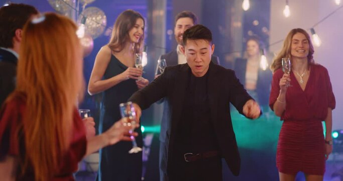 Attractive happy asian man employee rocking the corporate party dancing in middle of excited crowd. Socializing event. Social meeting. Company holiday.