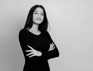 Beautiful young woman with long black hair posing in dress on grey background