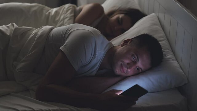 The man texting messages, while his girlfriend is sleeping