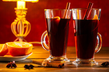 Mulled wine for two. Mulled wine in glass with cinnamon, spices and orange on wooden table.