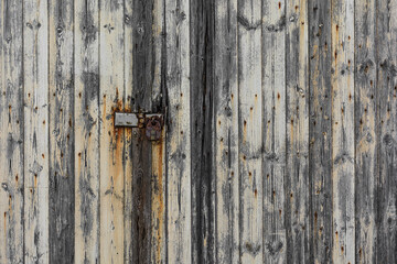 Rustic worn wooden gate locked by a heavy old padlock.