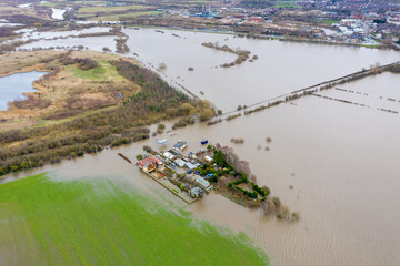 Obraz premium Aerial drone photo of the town of Allerton Bywater near Castleford in Leeds West Yorkshire showing the flooded fields and farm house from the River Aire during a large flood after a storm.