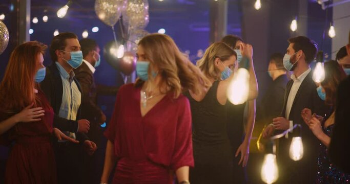 Multi-ethnic Formal Corporate People Dancing in Medical Masks Having Fun on Company Business Party Indoors. Coronavirus. Social Distance Concept.