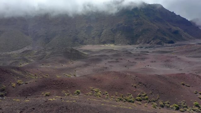 Scenic panorama of Haleakala volcano craters, cloudy sky on summer rainy day. Hiking trail in wilderness, outdoors adventure aerial 4K. Beautiful volcanic land. Famous Maui landscape, Hawaii island